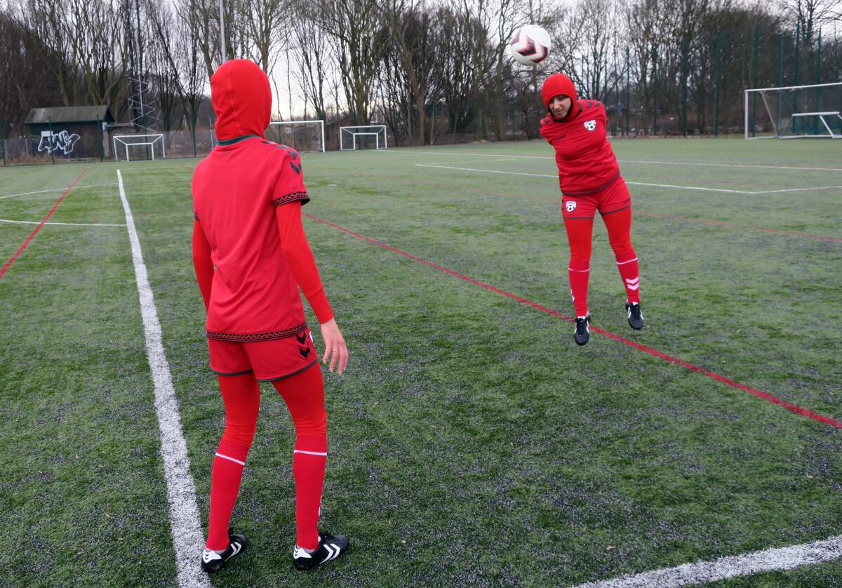 Shabnam Mabarz, seen from behind, watches as Khalida Popal heads the ball