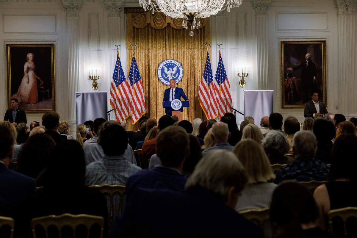 Kennedy flanked by flags onstage before a crowd