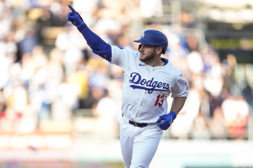 Los Angeles Dodgers' Max Muncy (13) celebrates as he runs the bases after hitting a home run.