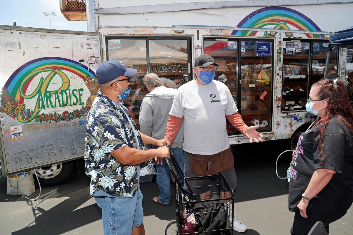 Mike Robbins, center, from Paradise Cigars, speaks w couple Della Hernandez, and, Steven,  the O.C. Swap Meet