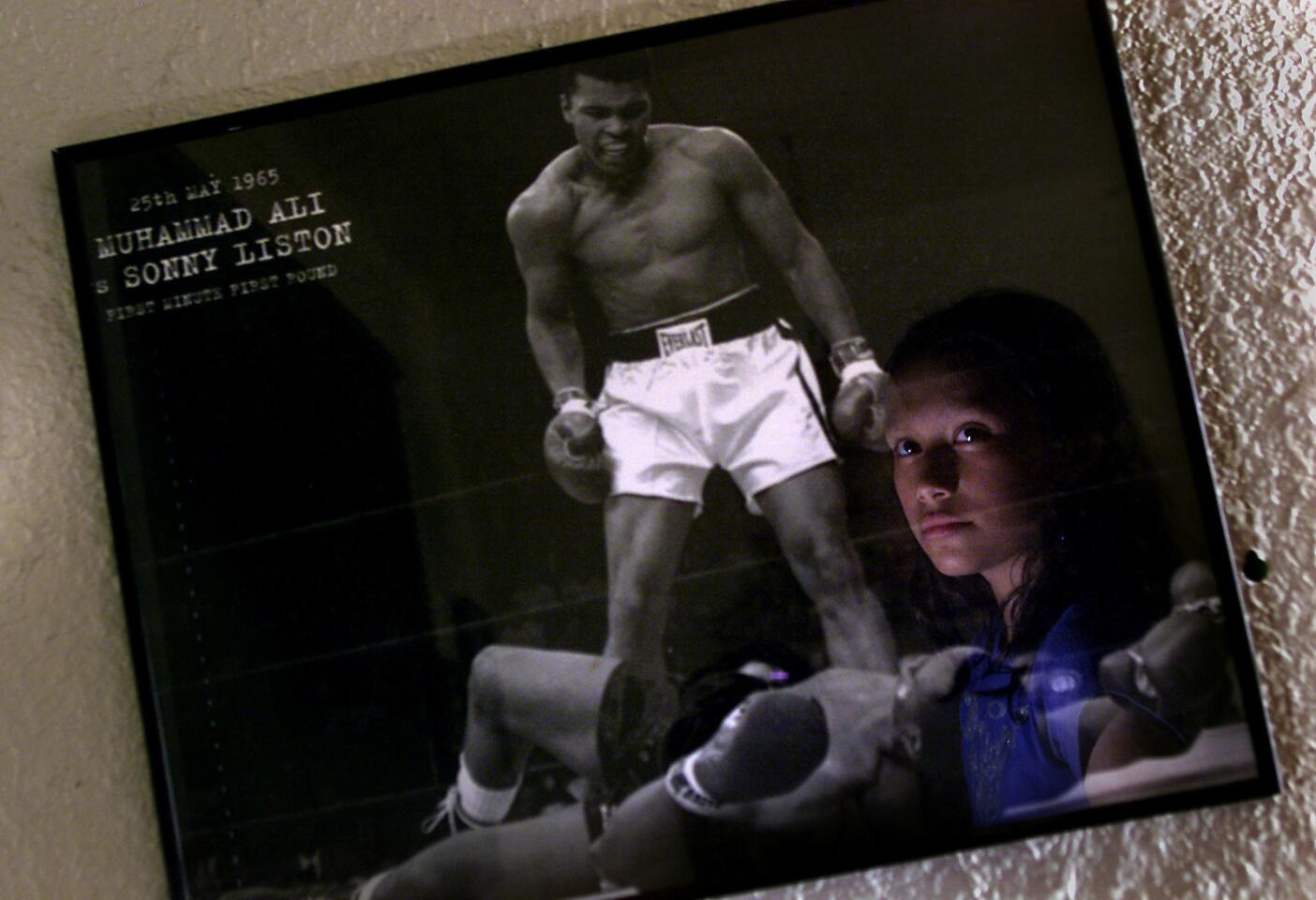 Cusack, Anne -- - In a portrait at her home Seneisa Estrada age 10 looks at the one framed poster in her living room that shows one of her idols and shows one of the few items in her home that reflects her interest in boxing as her mother is not fond of the idea that she boxes. Seneisa Estrada does her homework after school. Then heads for the Hollenbeck youth Center for training with her friend Frankie Gomez age 10. The two hope to compete in the upcoming Silver Gloves tournament in Long Beach. This will be one of their last days of training at the youth center as they plan to move to a new gym. 10/03/2002 Anne cusack/Los Angeles Times