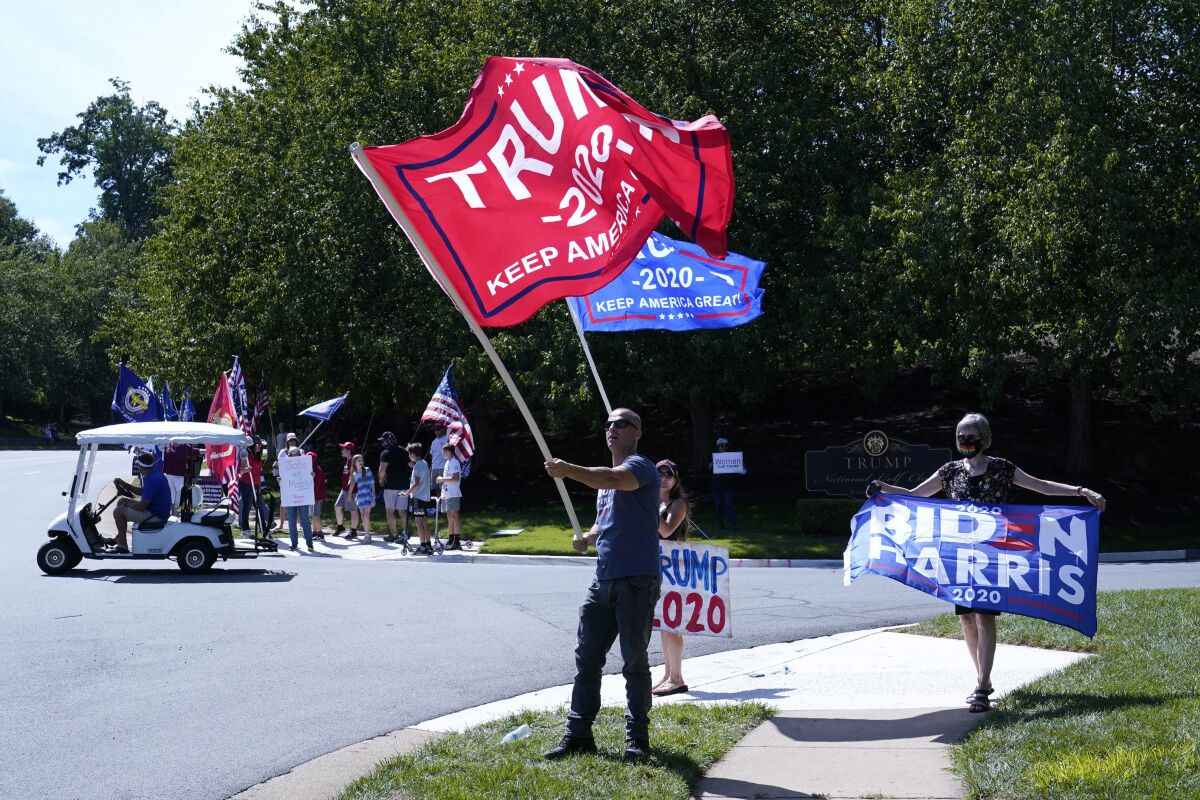 Protesters and supporters of President Donald Trump gather outside Trump National Golf Club in Sterling, Va., Saturday, Sept. 5, 2020, before the departure of Trump's motorcade. (AP Photo/Patrick Semansky)