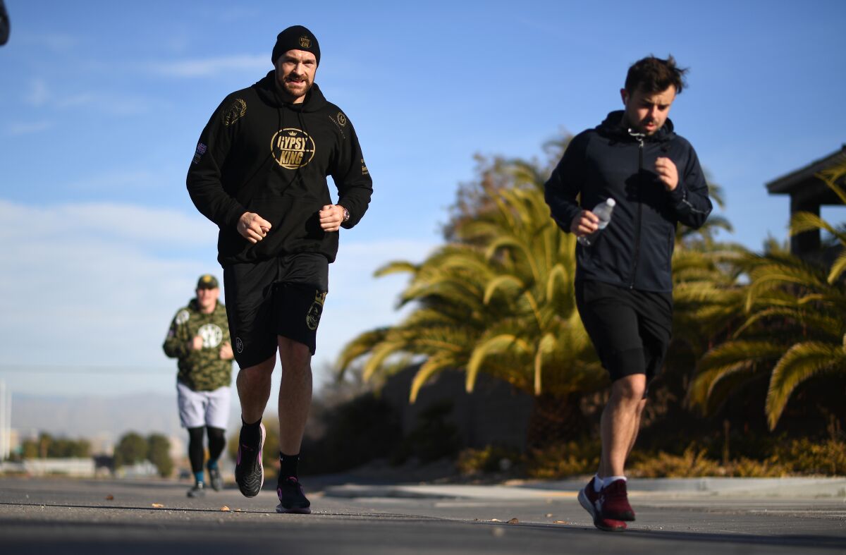 Tyson Fury, left, jogs with his trainers during a morning workout in Las Vegas.