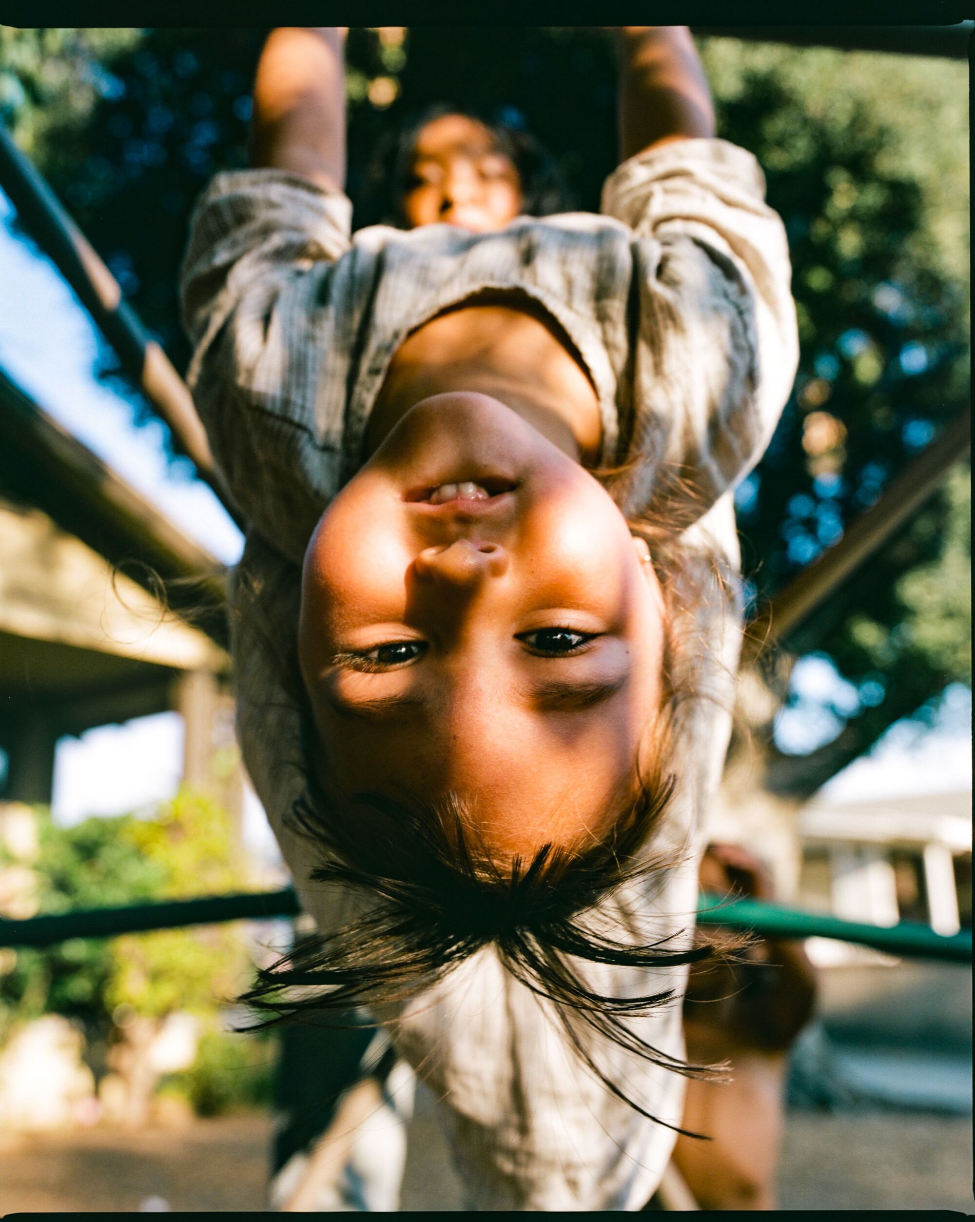 Synmia's daughter upside down on a jungle gym