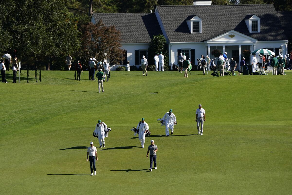 Golfers and caddies walk up the first fairway during the second round of the Masters golf tournament Friday.
