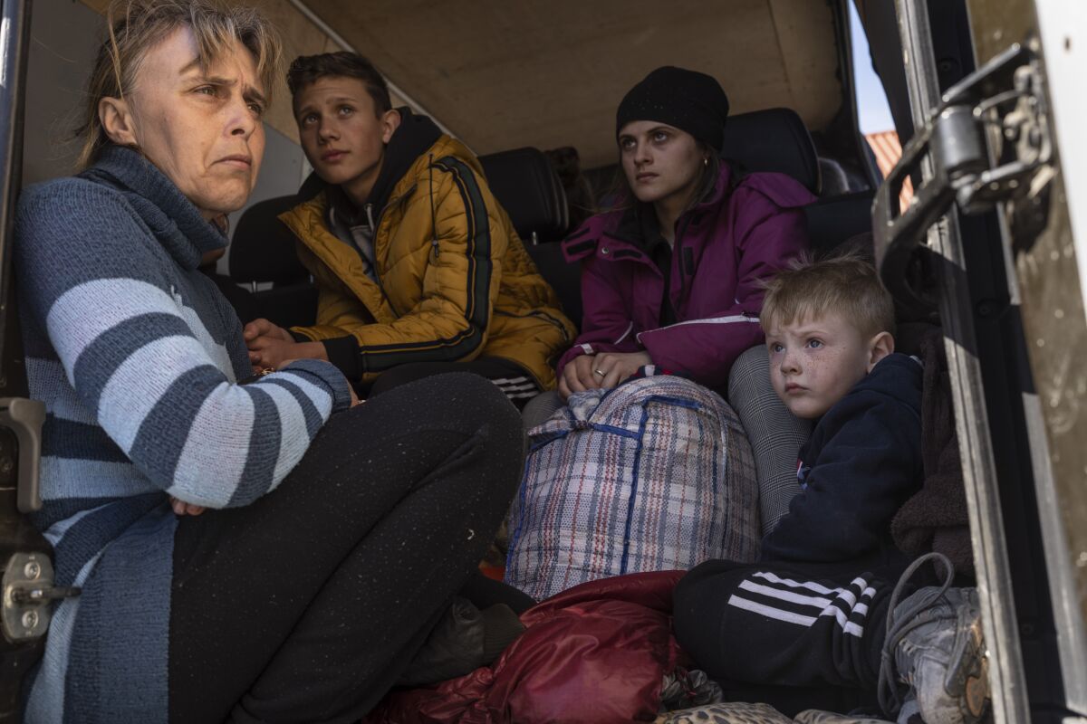 Oksana Gavrielutca 41, from left, sits at the back of a bus with her children Oleg 18, Diana, 17, and Vlad, 5, after they fled from Snigiriovka village, in Mikolaiv district, Ukraine, on Thursday, April 7, 2022. (AP Photo/Petros Giannakouris)