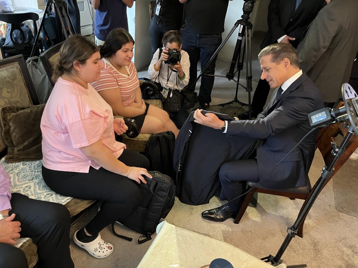 L.A. schools Supt. Alberto Carvalho shows two students a backpack. 