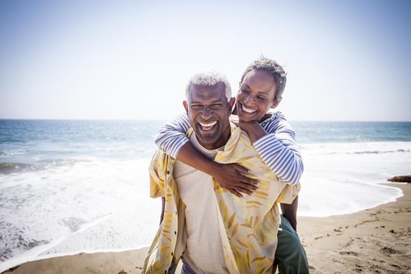 A beautiful senior black couple piggyback on the beach