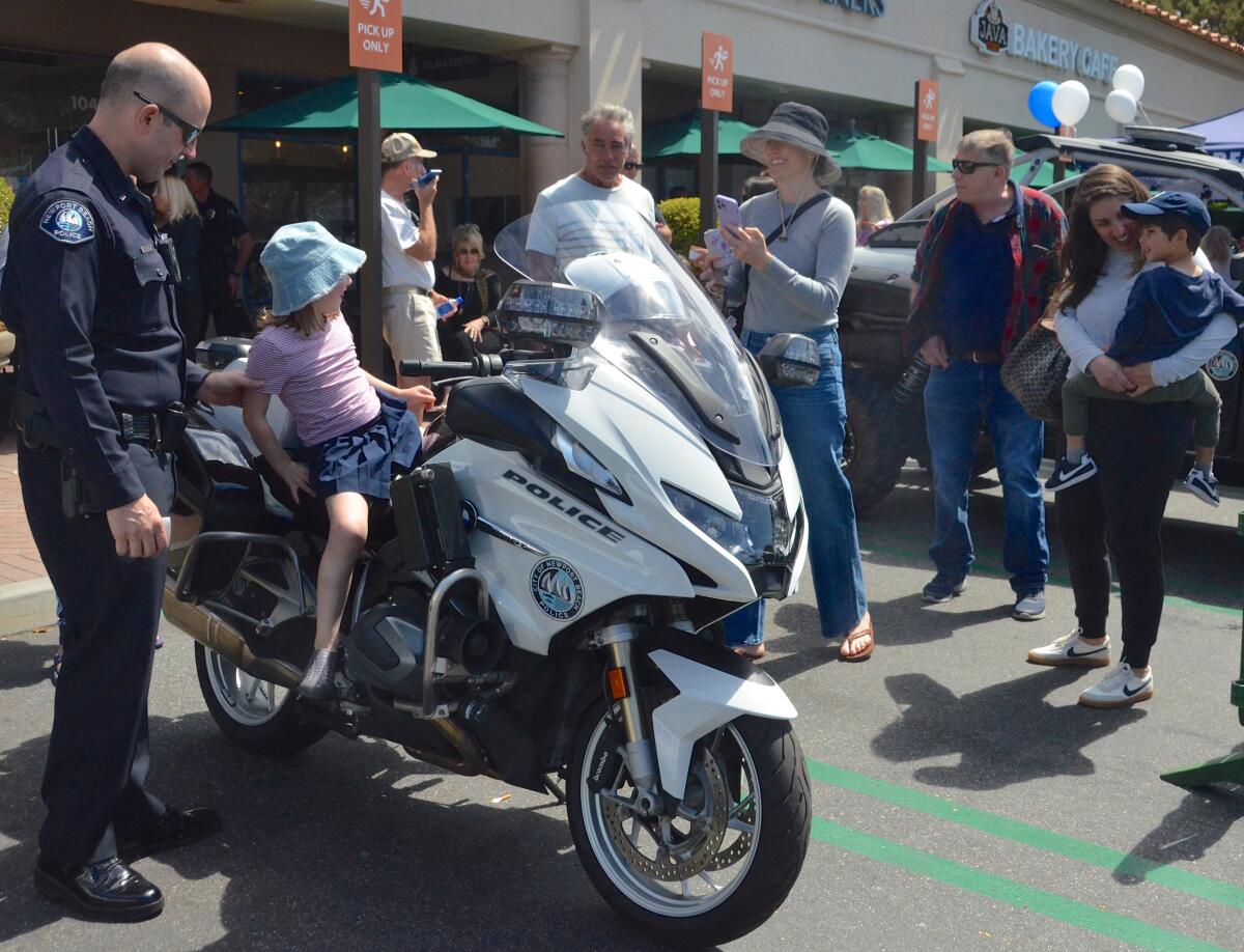 Lt. Eric Little attends to kids taking turns sitting on a police motorcycle Saturday.