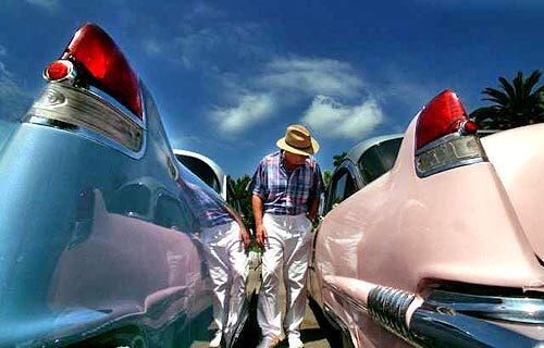 Car collector Gerald McCrystal of New York walks between a 1954 Coupe, left, and a '56 Sedan de Ville on display at the Great Labor Day Cruise and Car Show in Costa Mesa. The annual event draws classic and antique car devotees from all over the country. This year's show will be held Sept. 2-4 at the Orange County Fair & Exposition Center.
