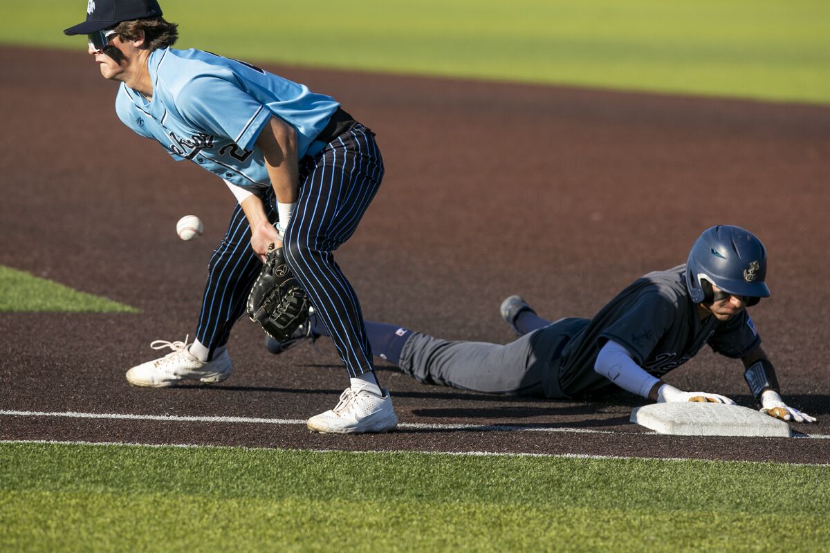 Newport Harbor's Adair Bisoso dives back into first as Corona del Mar's Nick Salmon blocks a throw on a back pick on Friday.