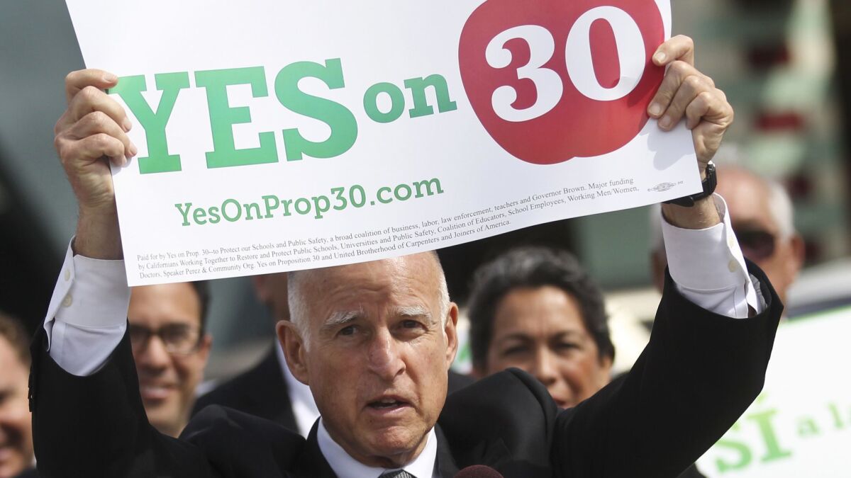 Gov. Jerry Brown holds up a sign in support of Proposition 30 while visiting a San Diego school on Oct. 23, 2012, in San Diego. The ballot measure passed with 55% of the vote.