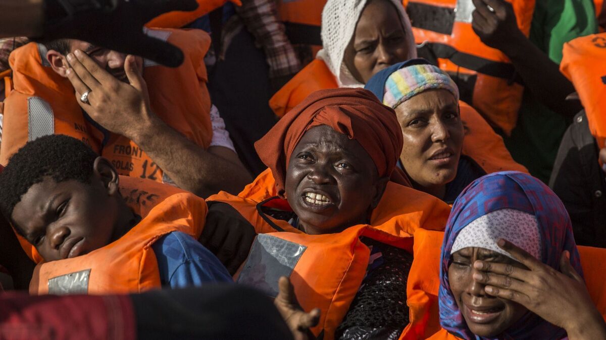 Migrants aboard a rubber dinghy off the Libyan coast receive aid from rescuers aboard the Open Arms aid boat on June 30, 2018.