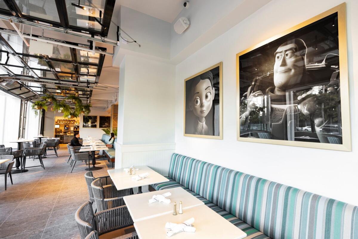 Stoic black and white portraits of Pixar characters overlook a dining area. 