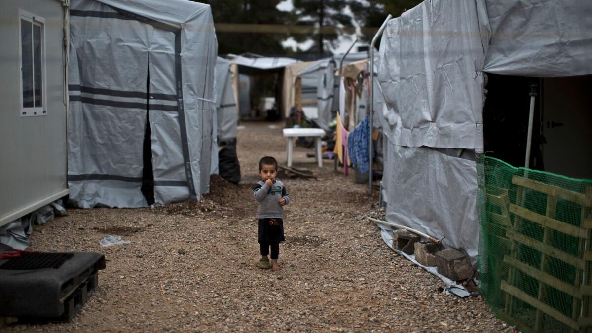 A Syrian child walks between shelters at a refugee camp located north of Athens, Greece, on Dec. 28.