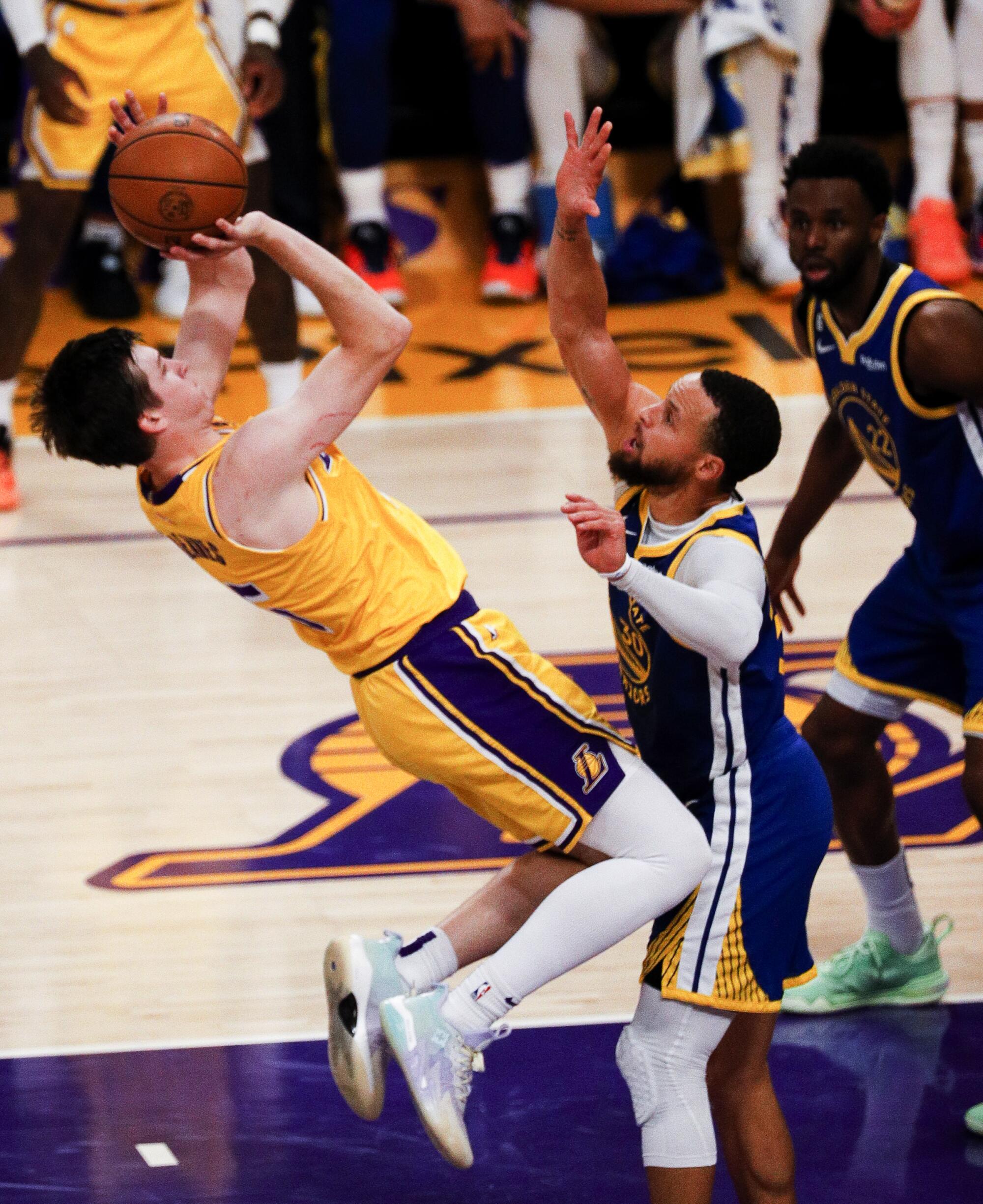 Lakers guard Austin Reaves, left, shoots after being fouled by Warriors guard Stephen Curry during the first half.