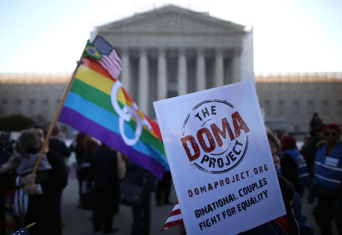 People carry banners and flags during a rally in front of the U.S. Supreme Court on Wednesday, hours before the high court is scheduled to hear arguments on whether Congress can withhold federal benefits from legally wed gay couples by defining marriage as only between a man and a woman.