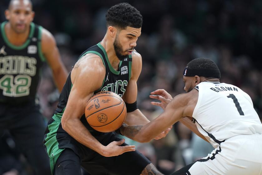 Boston Celtics forward Jayson Tatum, center, grapples for control of the ball with Brooklyn Nets forward Bruce Brown (1) in the first half of Game 1 of an NBA basketball first-round Eastern Conference playoff series, Sunday, April 17, 2022, in Boston. (AP Photo/Steven Senne)