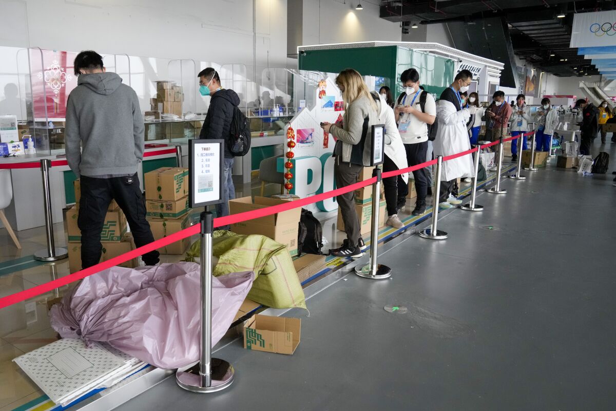 People queue with their parcels outside the post office at the Main Press Center at the 2022 Winter Olympics, Friday, Feb. 11, 2022, in Beijing. (AP Photo/Mark Baker)