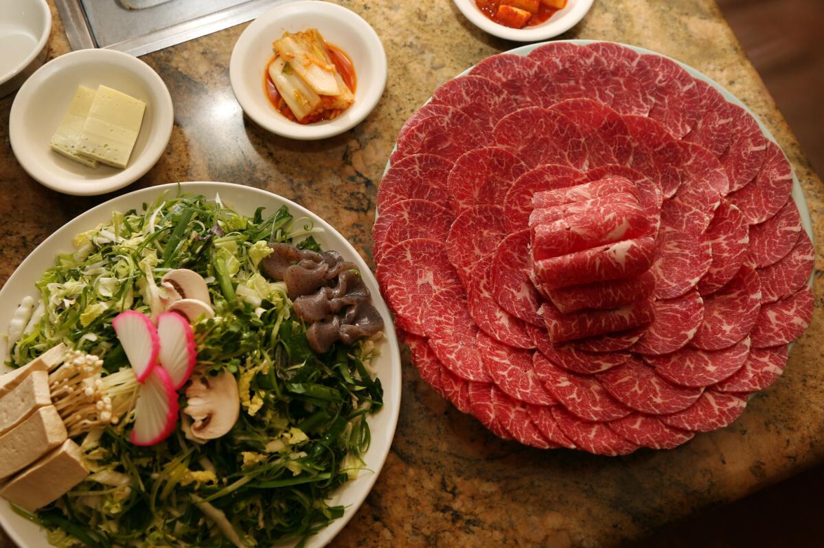 Prime beef and a plate of greens and other veggies, ready to go into the hot pot at Seoul Garden in Koreatown.