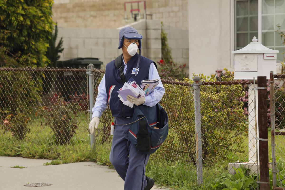 A letter carrier wears gloves and a mask in Torrance.