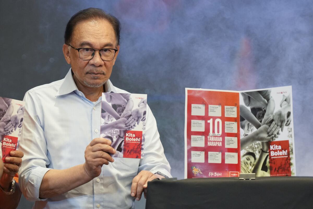 Malaysian opposition leader Anwar Ibrahim shows a copy of manifesto of his Pakatan Harapan (The Alliance of Hope) at a hotel in Klang, Malaysia Wednesday, Nov. 2, 2022. With a battle cry of “We Can,” reformist opposition leader Anwar Ibrahim has launched what could be his last chance to fulfill a 2-decade-long quest to become Malaysia’s leader in Nov. 19, 2022 general elections. (AP Photo/Vincent Thian)
