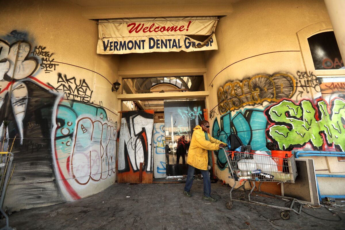 A man pushes a grocery cart outside an abandoned Koreatown building where homeless people live
