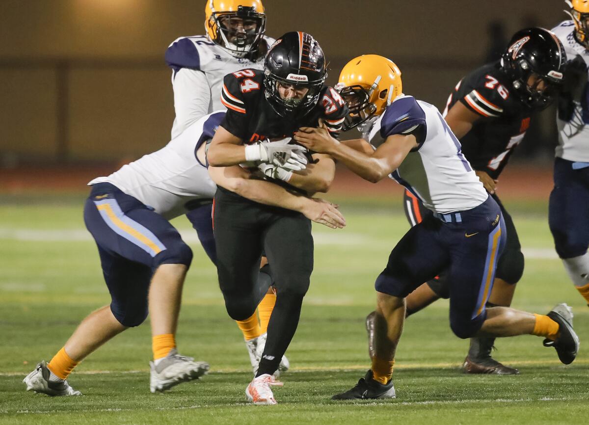 Huntington Beach running back Evan Riederich (24) runs through a gap and is met by a host of tacklers against Marina.