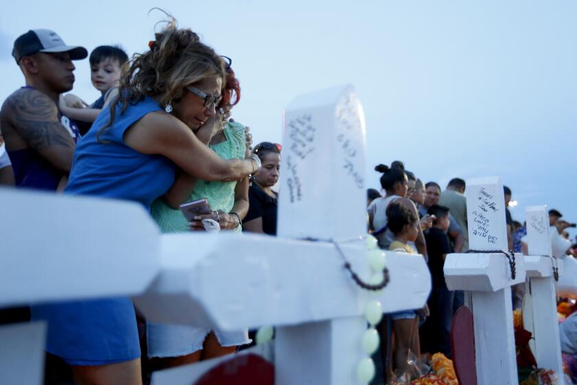 Rebecca Najera, left, hugs Elsa Escobar as they joined others gathered Monday, Aug. 5, 2019 in front of crosses representing the victims who died in the shooting at a Walmart in El Paso, Texas. (Vernon Bryant/The Dallas Morning News/TNS) ** OUTS - ELSENT, FPG, TCN - OUTS **