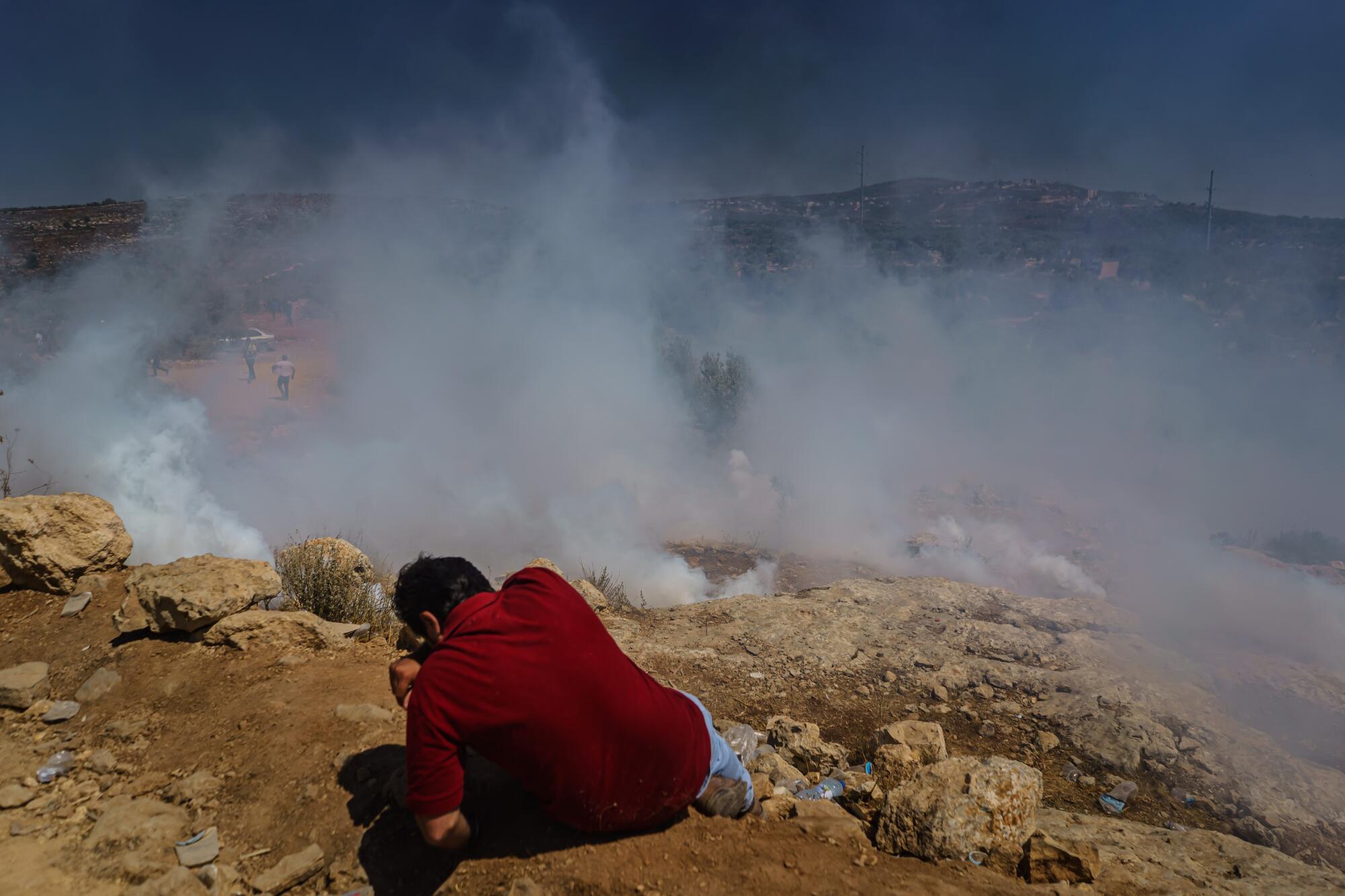 A Palestinian man chokes on tear gas during a protest 