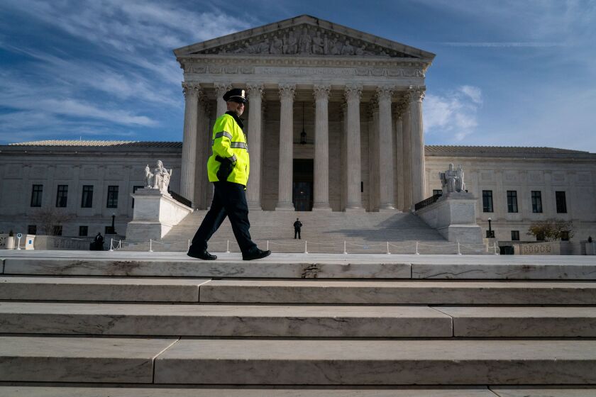 WASHINGTON, DC - DECEMBER 05: A Supreme Court Police Officer stands on the steps as protesters and supporters gather in front of the Supreme Court of the United States on Monday, Dec. 5, 2022 in Washington, DC. The High Court heard oral arguments in a case involving a suit filed by Lorie Smith, owner of 303 Creative, a website design company in Colorado who refused to create websites for same-sex weddings despite a state anti-discrimination law. (Kent Nishimura / Los Angeles Times)