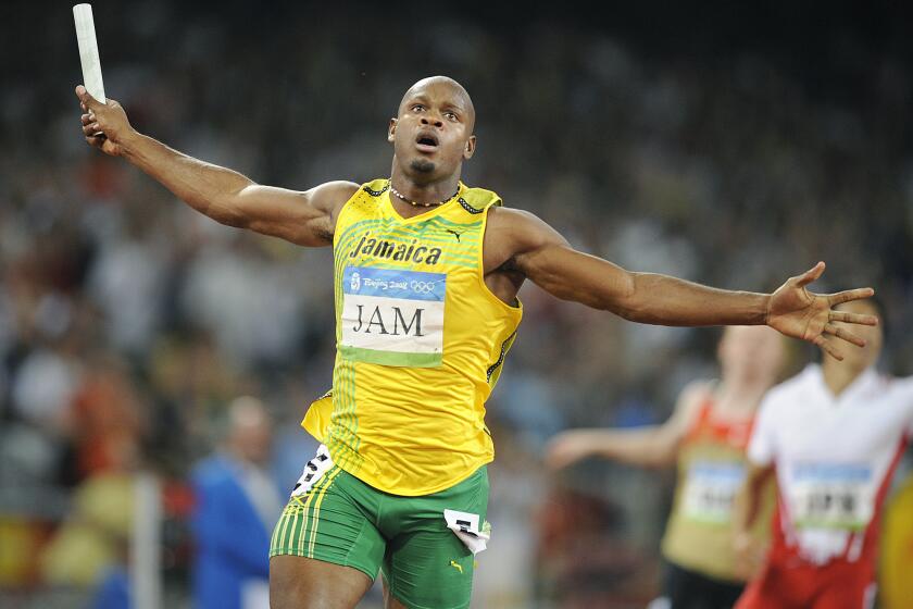 Jamaica's Asafa Powell carries the baton across the finish line for his team in the 400-meter relay at the 2008 Beijing Olympics.