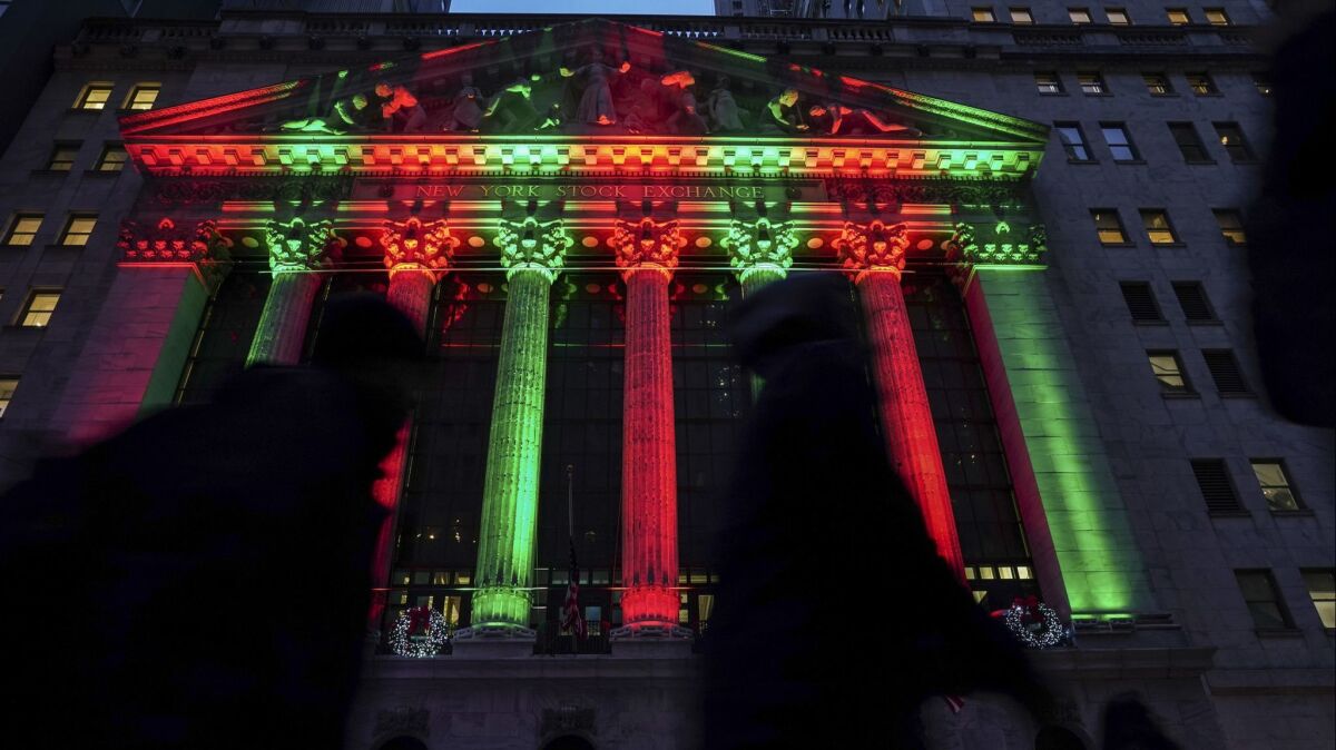 Pedestrians walk past the New York Stock Exchange, illuminated with holiday colors, on Dec. 17, 2018.