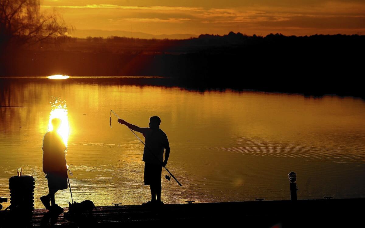 Two men fish from a dock in the delta near Stockton. State officials are more confident that there was enough water in reservoirs to meet human health and safety needs and provide some supplies for senior rights holders in the Sacramento and San Joaquin valleys.