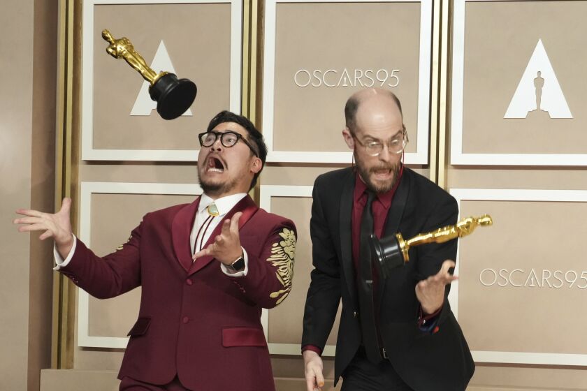 Daniel Kwan, izquierda, y Daniel Scheinert lanzan al aire sus premios de mejor película por "Everything Everywhere All at Once" al posar en la sala de prensa de los Oscars el 12 de marzo de 2023, en el Teatro Dolby en Los Angeles. (Foto Jordan Strauss/Invision/AP)