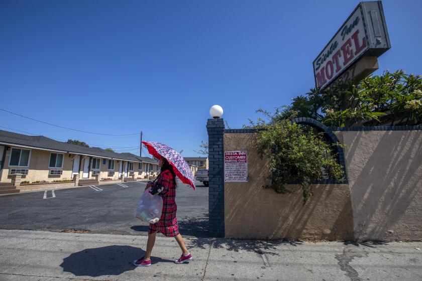 El Monte, CA - June 21: A woman walks past the Siesta Inn Motel in El Monte where two police officers were fatally shot after responding to a call in El Monte, CA on Tuesday, June 21, 2022, in El Monte, CA. (Francine Orr / Los Angeles Times)