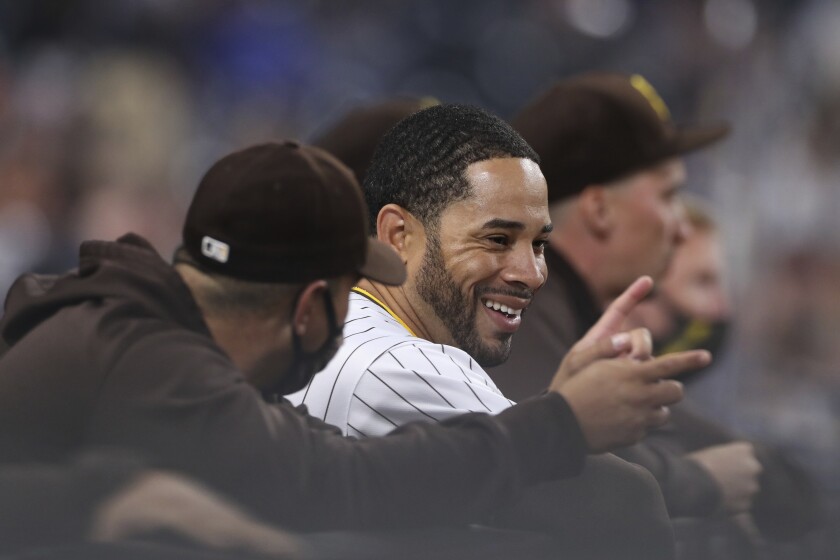 The Padres' Tommy Pham smiles while talking with a teammate 