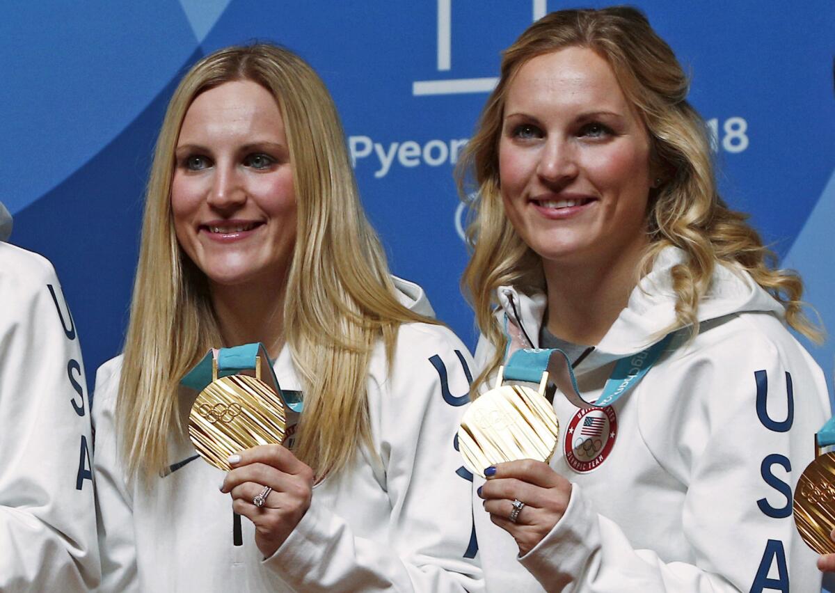 Team USA hockey players Monique Lamoureux-Morando and Jocelyne Lamoureux-Davidson celebrate after winning gold medals at the 2018 Winter Olympics.
