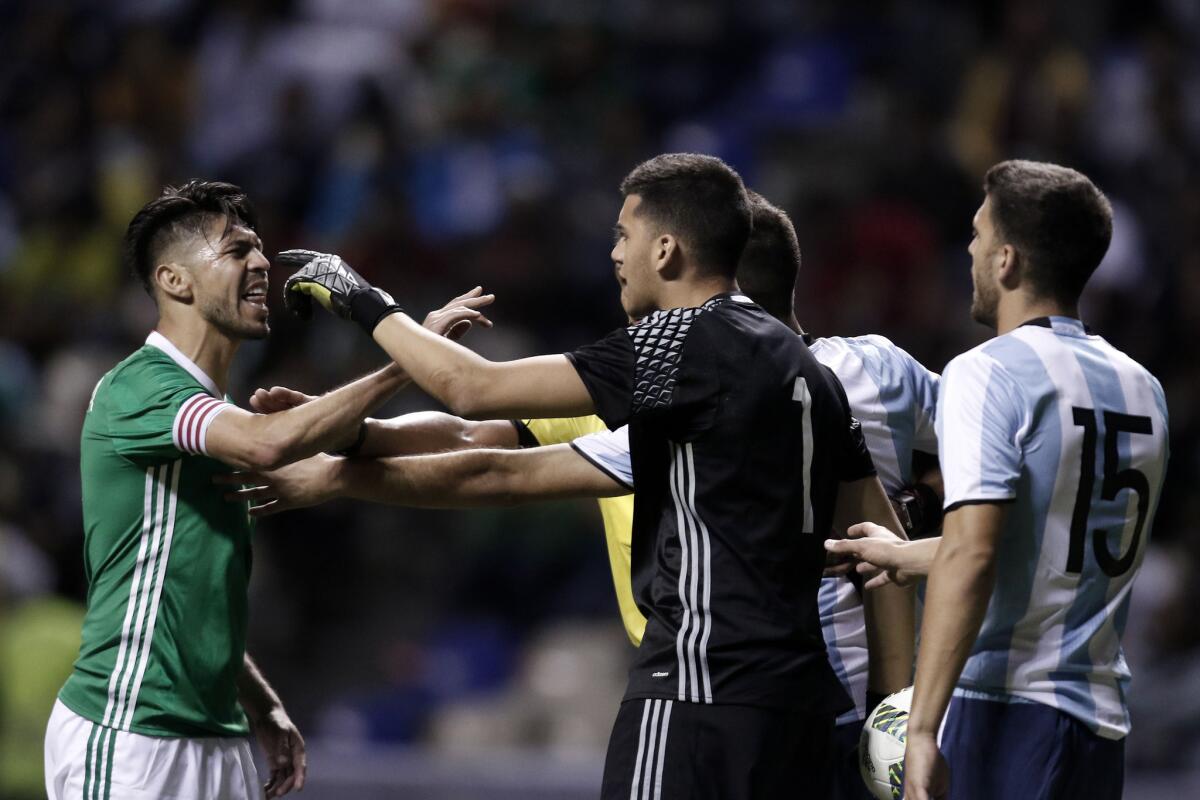 El jugador Oribe Peralta (i) de la selección Sub23 de México discute con Gerónimo Rulli (c) de Argentina hoy, jueves 28 de julio de 2016, durante un partido amistoso rumbo a los Juegos Olímpicos de Río de Janeiro 2016, en el estadio Cuauhtémoc, en Puebla (México).