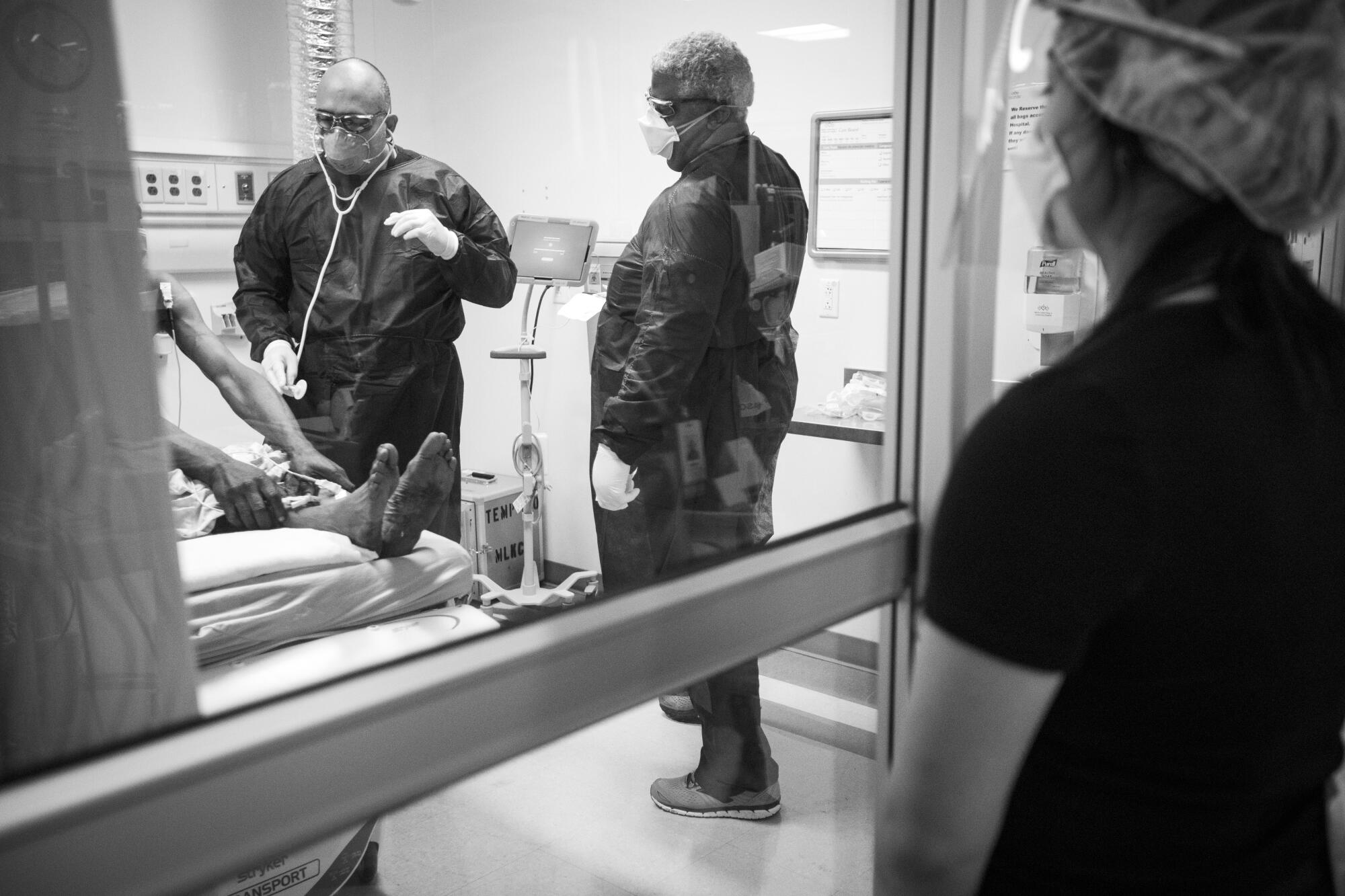 Dr. Oscar Casillas, left, and registered nurse Jesse Lynwood, center, work with a patient at MLK Community Hospital.