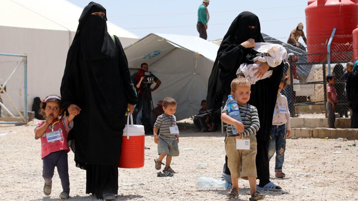 Wives of Islamic State fighters walk with their children upon deportation from Al Hawl camp for the displaced in Hasakah province in northeastern Syria on June 3.