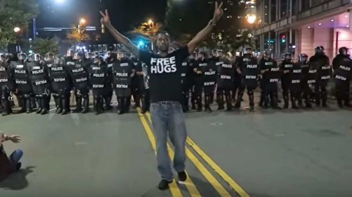 Ken E. Nwadike Jr. stand in front of a line of police officers in North Carolina. (Free Hugs Project/YouTube)