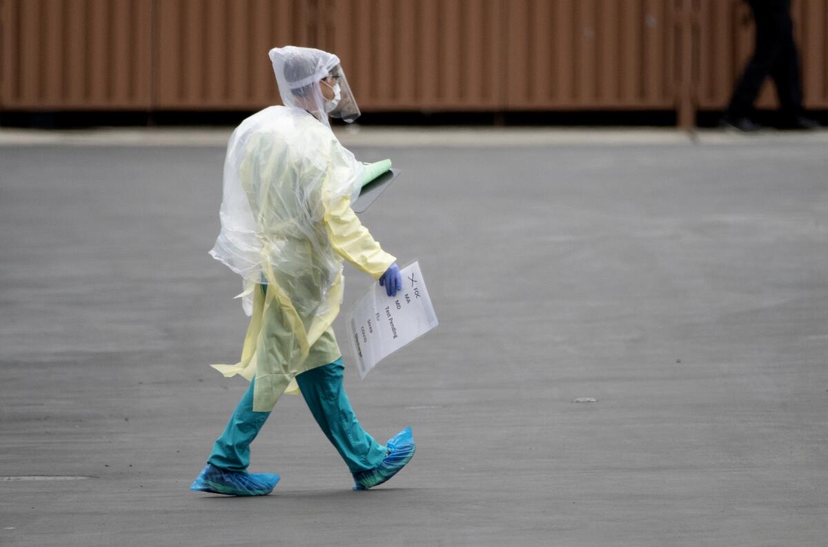 A medical professional carries a car tag used to identify symptoms at a drive-through coronavirus testing place in March.