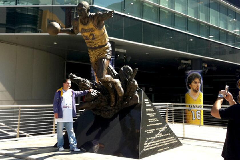 Lakers fan Luis Ramirez gets his photo taken at the Magic Johnson statue outside Staples Center on Wednesday evening.