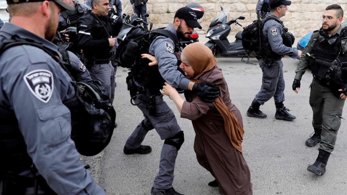An Israeli police officer pushes back a Palestinian woman outside the Old City of Jerusalem after Israeli forces closed the entrance to Al Aqsa mosque compound on March 12, 2019.