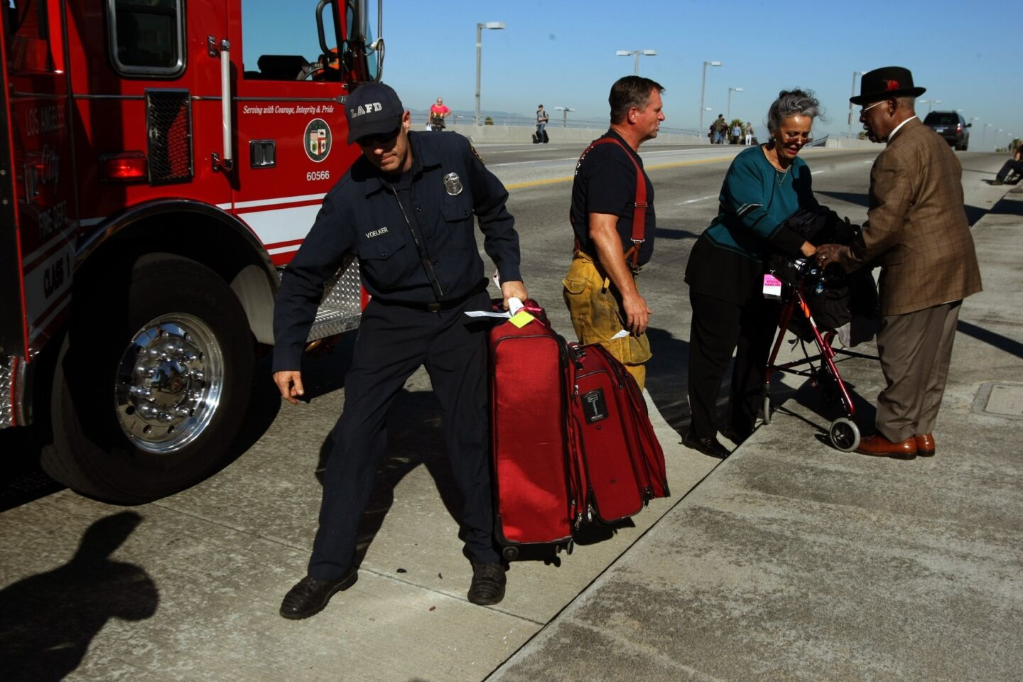 Joseph Heyward, 87, right, and his wife get help with their luggage and a ride from Los Angeles firefighters.