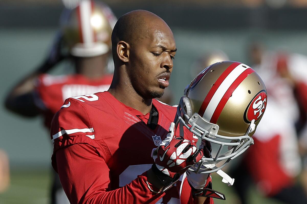 FILE - In this Jan. 15, 2014 file photo, San Francisco 49ers cornerback Carlos Rogers adjusts his helmet during practice at an NFL football training facility in Santa Clara, Calif. Ten former NFL players have been charged with defrauding the leagues healthcare benefit program. They include five who played on the Washington Redskins, including Clinton Portis and Carlos Rogers. (AP Photo/Jeff Chiu)