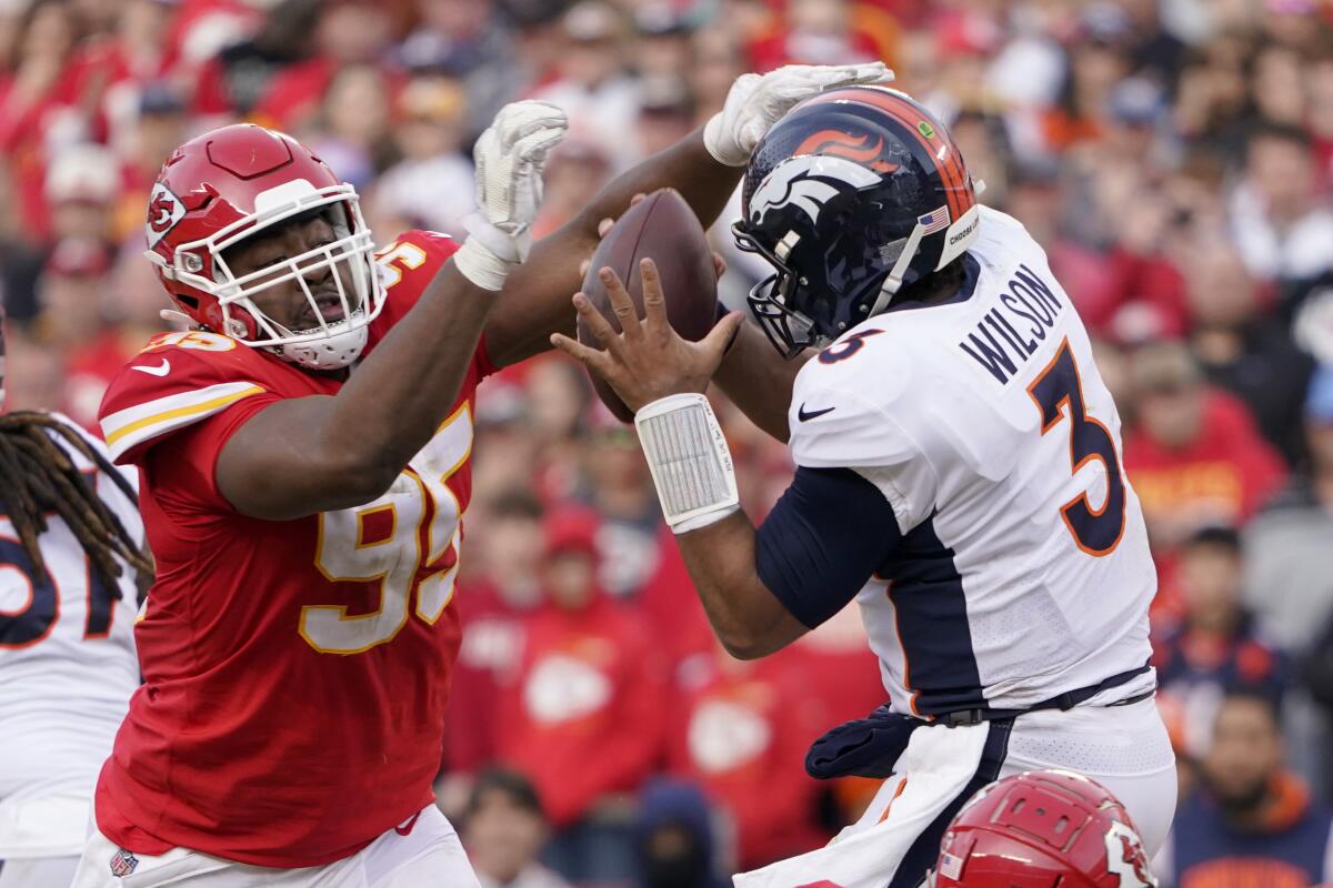 Denver Broncos quarterback Russell Wilson, right, holds the ball under pressure from Kansas City Chiefs defensive tackle Chris Jones (95) during the second half of an NFL football game Sunday, Jan. 1, 2023, in Kansas City, Mo. (AP Photo/Ed Zurga)