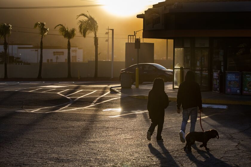 SAN JACINTO, CA - NOVEMBER 24, 2022: Residents walk to a darkened mini mart after powerful winds forced Southern California Edison to shut off the power to the area on Thanksgiving day November 24, 2022 in San Jacinto, California. The power is out in the area of Highway 74 and Vista Place. The San Ana winds will continue through Friday.(Gina Ferazzi / Los Angeles Times)