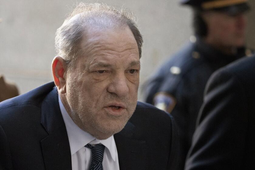 Harvey Weinstein hunches over in a dark suit and tie.